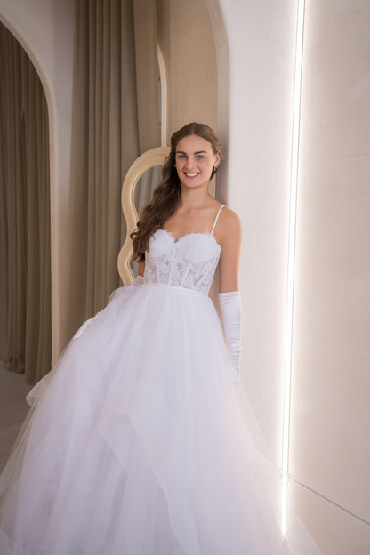 Woman in a white wedding dress standing in a softly lit room.