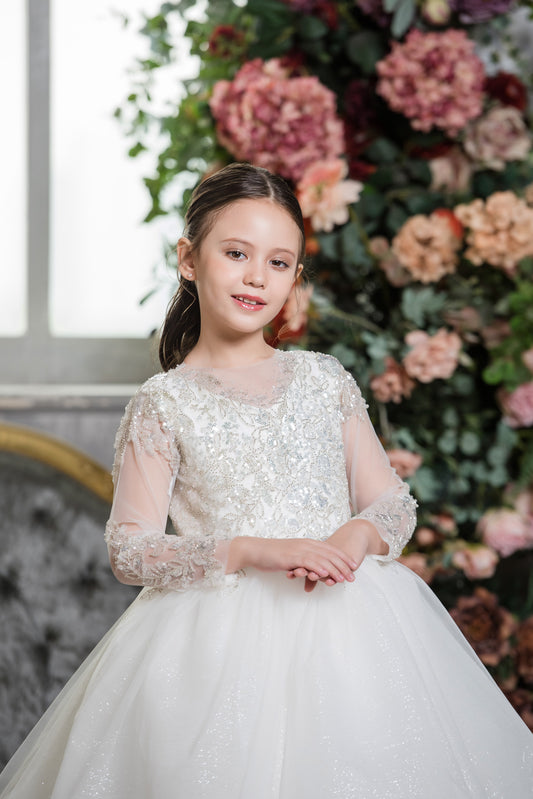 Young girl in a white dress standing in front of a floral arrangement
