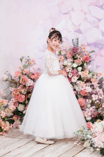 Woman in a white dress standing in front of a floral backdrop