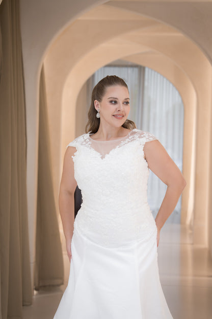 Woman in a white wedding dress standing in an elegant archway.