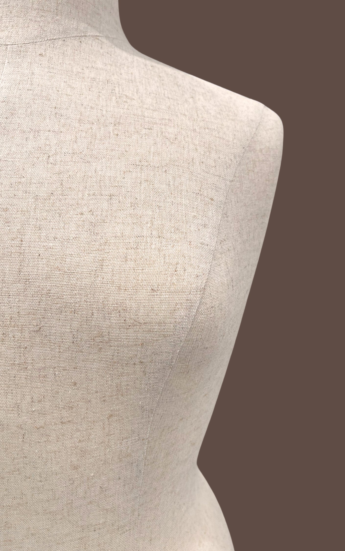 Mannequin torso with beige fabric on a brown background