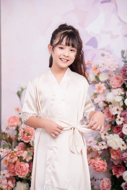Young girl in a white dress standing in front of a floral background