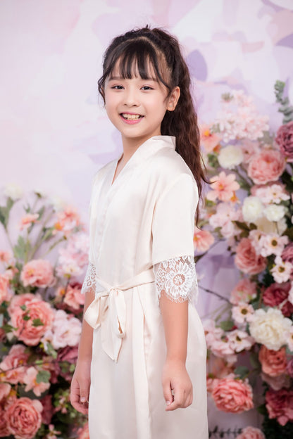 Young girl in a white dress standing in front of a floral background