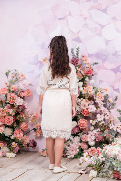 Woman in a white dress with 'flower girl' text standing in front of floral decorations.