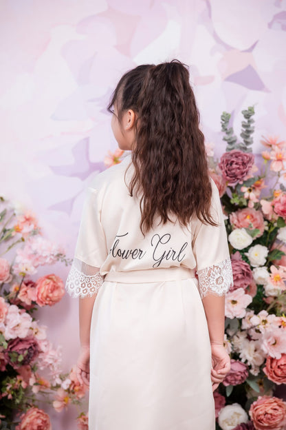 Person wearing a 'Flower Girl' robe in front of a floral backdrop