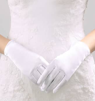 White gloves worn by a person in a white dress against a neutral background