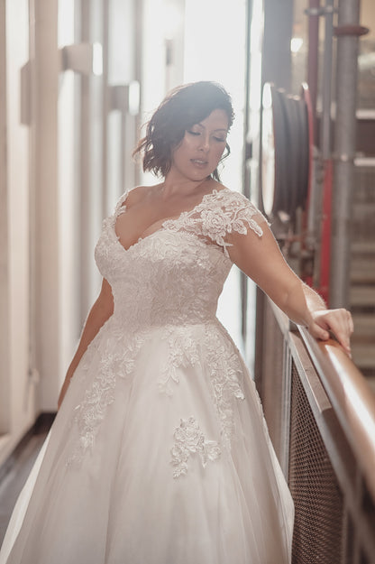 Woman in a white lace wedding dress standing indoors