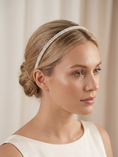Woman wearing a pearl headband against a neutral background