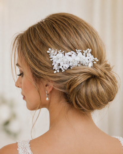 Woman with elegant hair styled with a decorative white hairpiece against a neutral background
