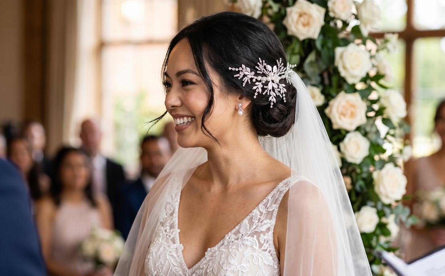 Bride in a wedding dress with a veil and floral hairpiece, smiling at a ceremony.