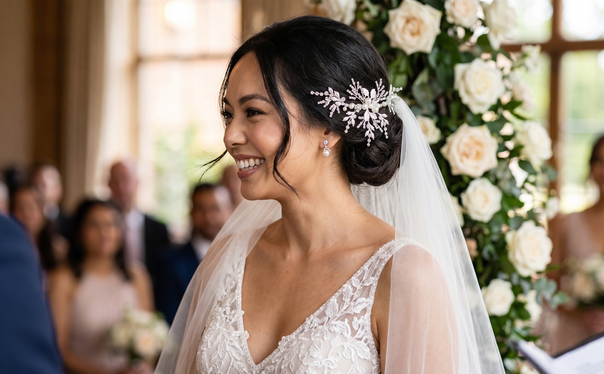 Bride in a wedding dress with a veil and floral hairpiece, smiling at a ceremony.