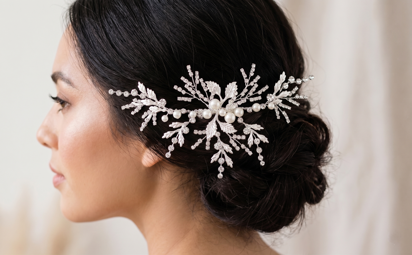Woman wearing a decorative hairpiece with pearls and crystals on a neutral background