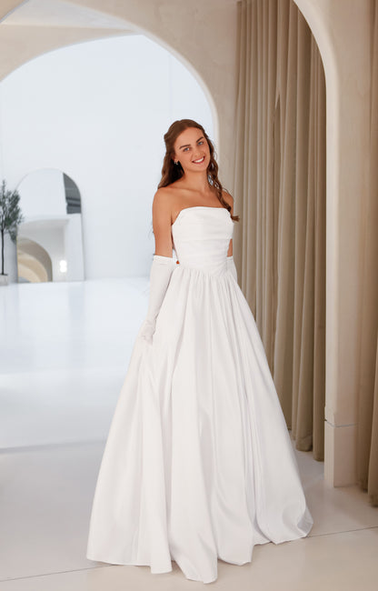 Woman wearing a white strapless gown in a bright room with arches.
