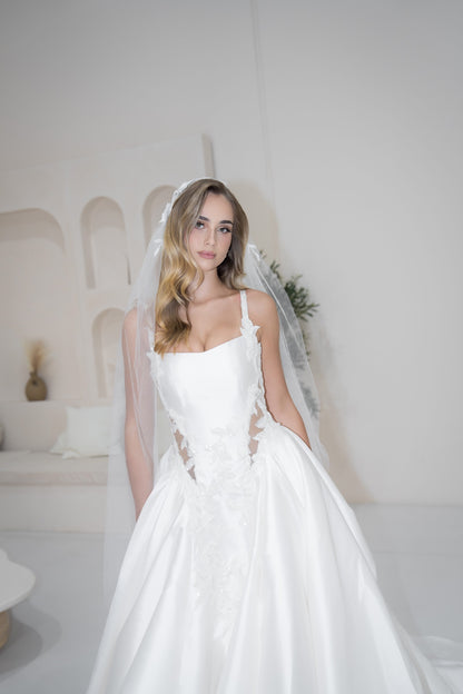 Woman in a white wedding dress with a veil in a minimalistic room.