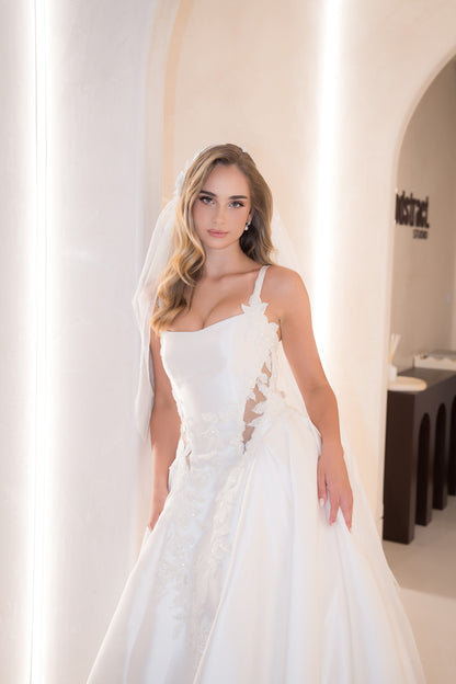 Woman in a white wedding dress standing in a bright room with a blurred background