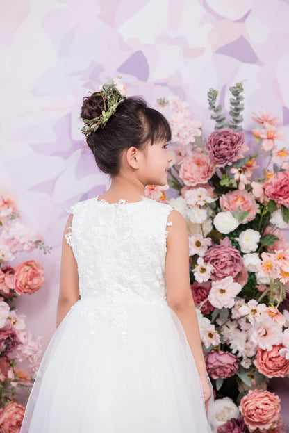 Woman in a white dress standing in front of a floral backdrop