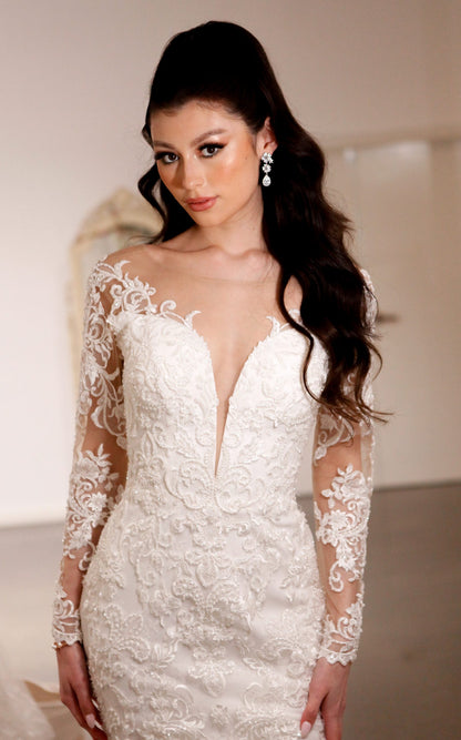 Woman wearing a white lace wedding dress with long sleeves.