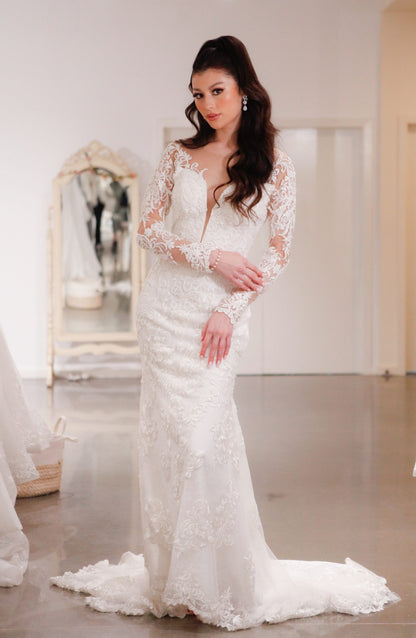 Woman wearing a white lace wedding dress in a room with mirrors.