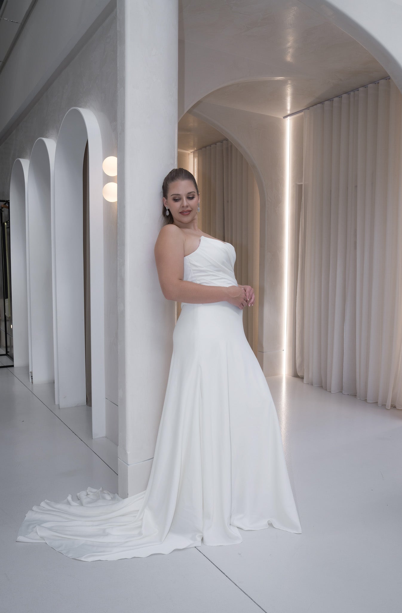 Woman in a white wedding dress standing in a modern architectural setting.