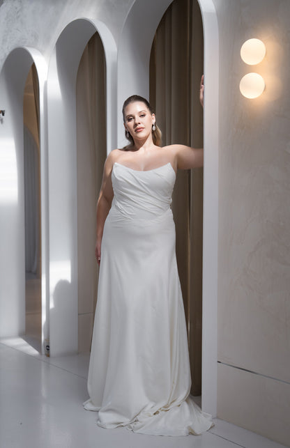 Woman in a white strapless gown standing in a modern architectural setting with arched doorways.
