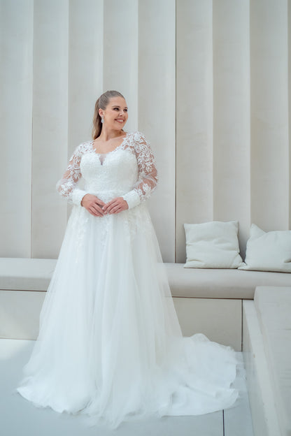 Woman in a white wedding dress standing in a modern interior setting.
