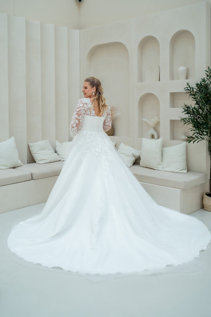 Woman in a white wedding dress standing in a modern interior setting.