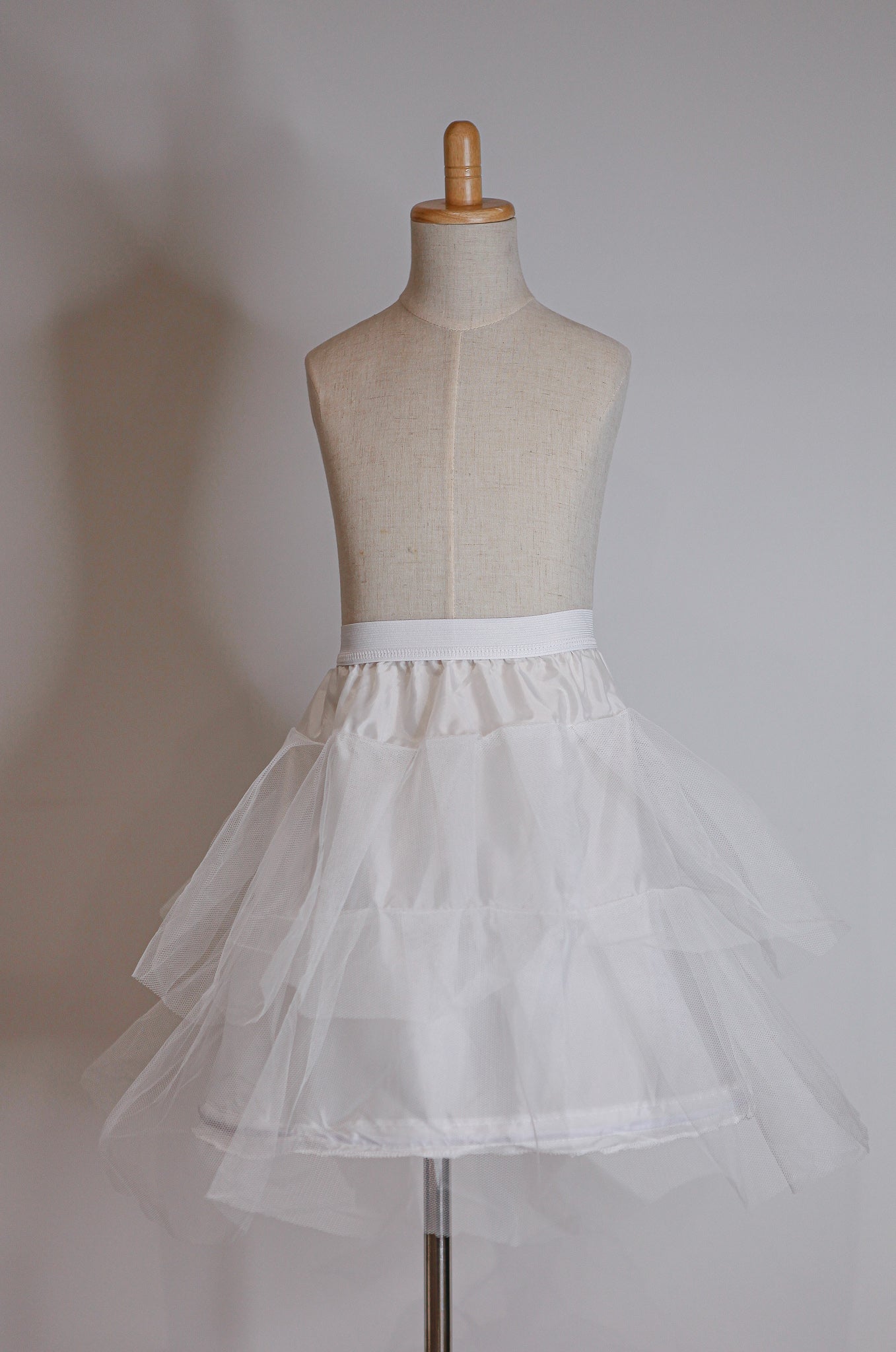 White petticoat on a mannequin against a plain background