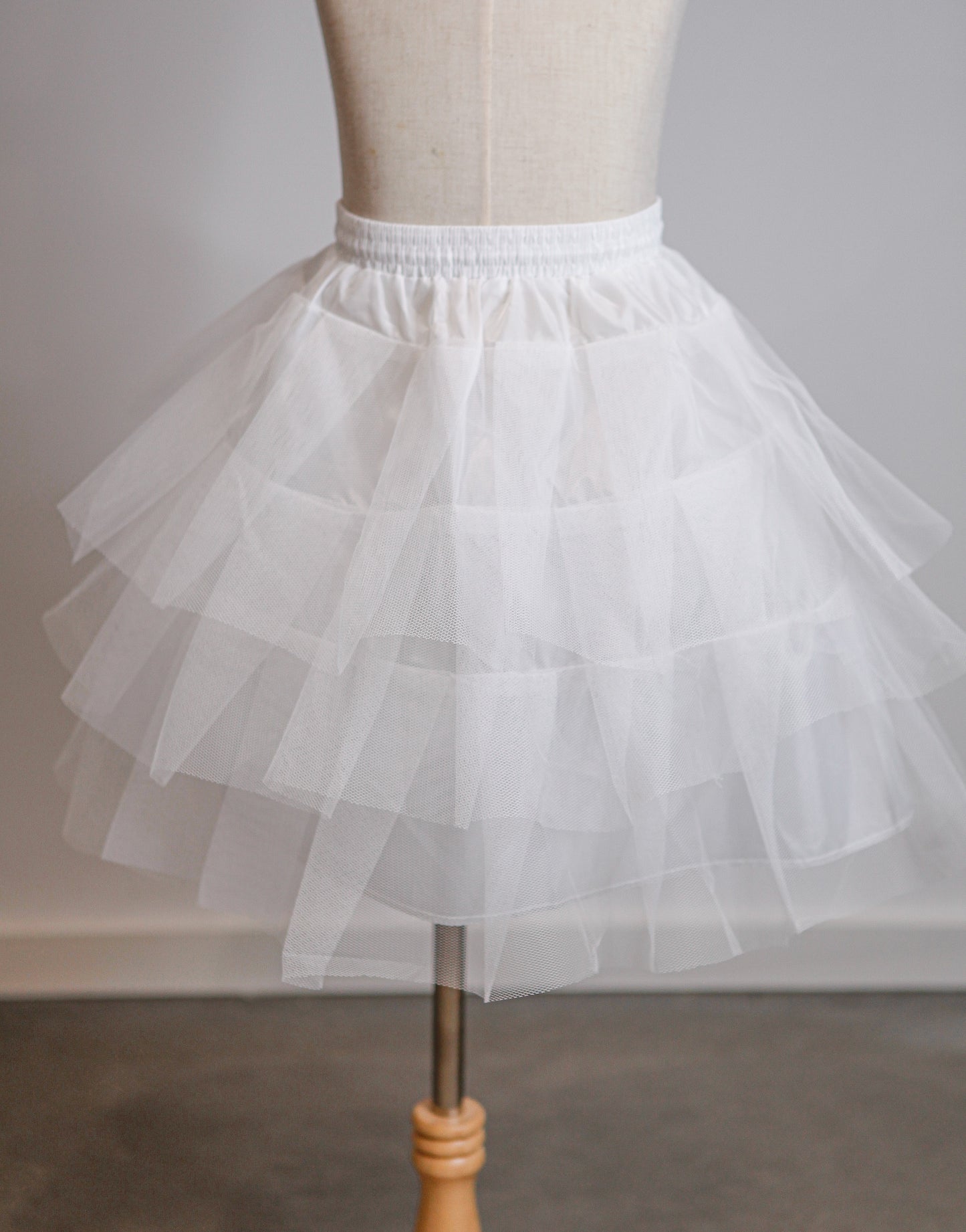 White petticoat on a mannequin against a plain background