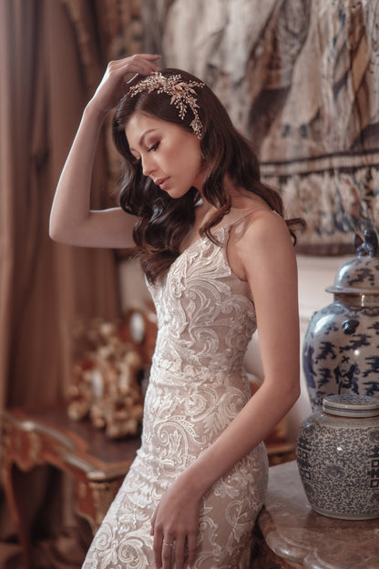 Woman in a lace dress adjusting her hair in an elegant room with decorative elements.