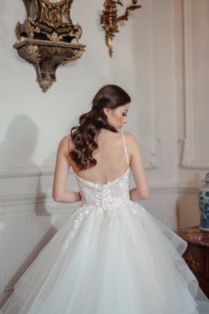 Woman in a white wedding dress standing in an elegant room with decorative wall pieces.