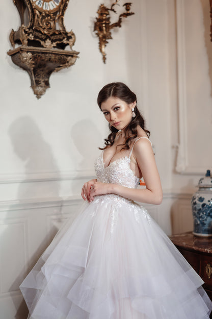 Woman in a white wedding dress standing in an elegant room with decorative elements.