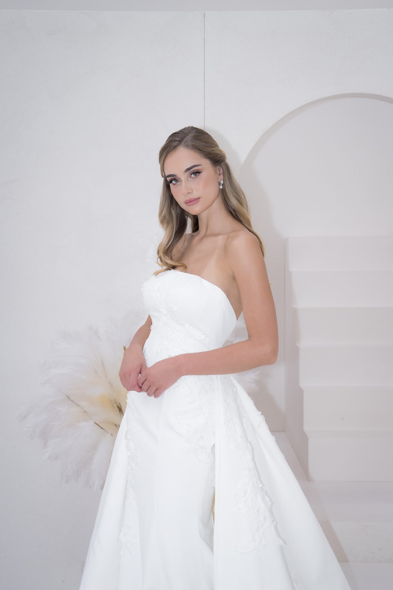 Woman in a white strapless gown against a plain background