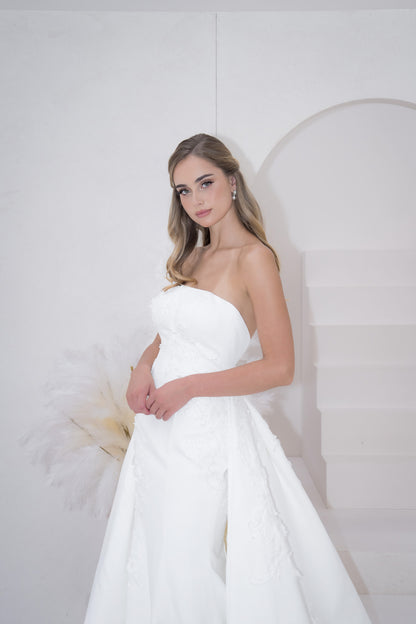 Woman in a white strapless gown against a plain background