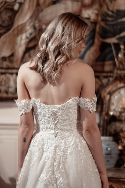 Woman wearing a white lace wedding dress with a decorative interior background