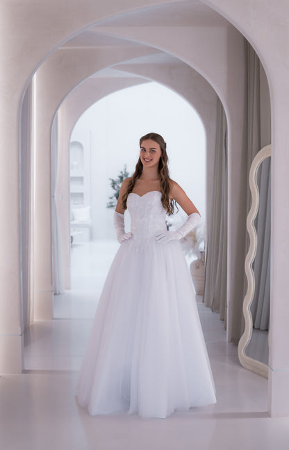 Woman in a white wedding dress standing in a modern architectural setting with arches.