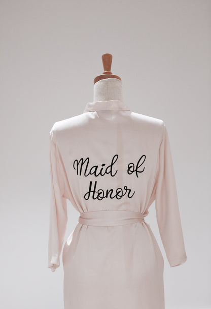 Pink robe with 'Maid of Honor' text on a mannequin against a white background