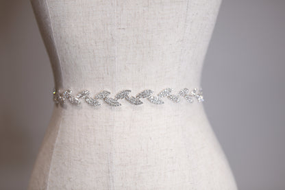 Silver belt with crystals on a mannequin against a neutral background