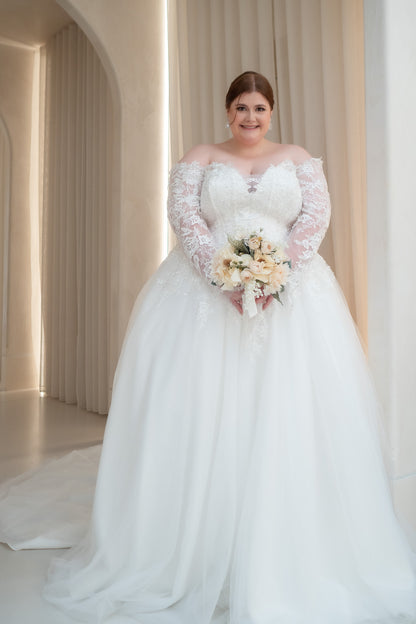 Woman in a white wedding dress holding a bouquet in a softly lit room.