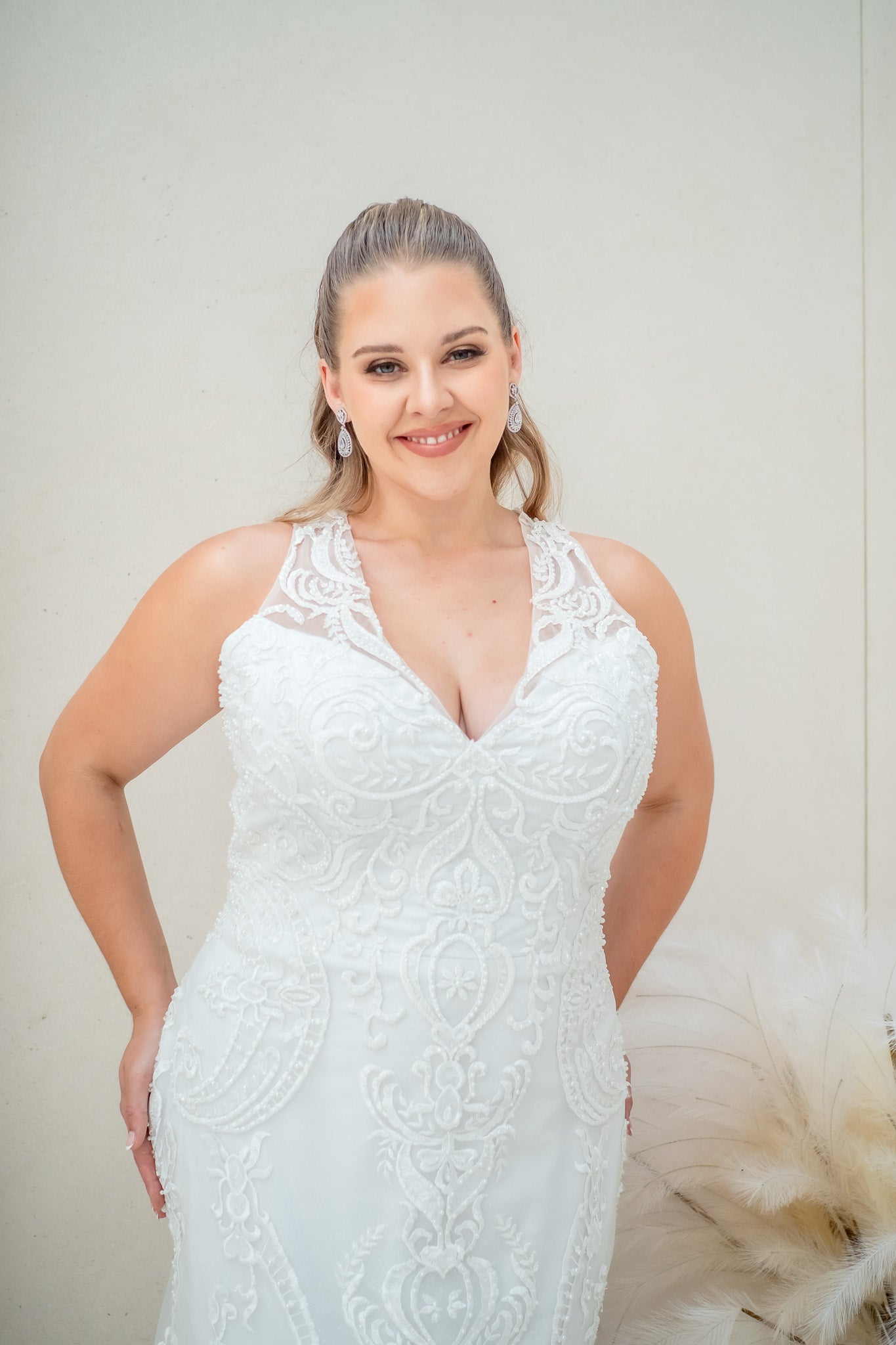 Woman wearing a white lace wedding dress against a plain background
