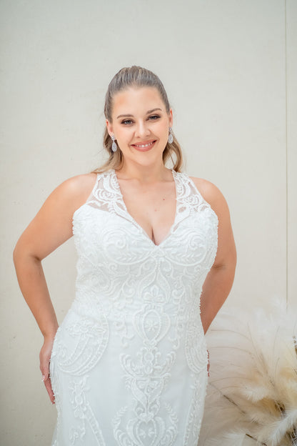 Woman wearing a white lace wedding dress against a plain background