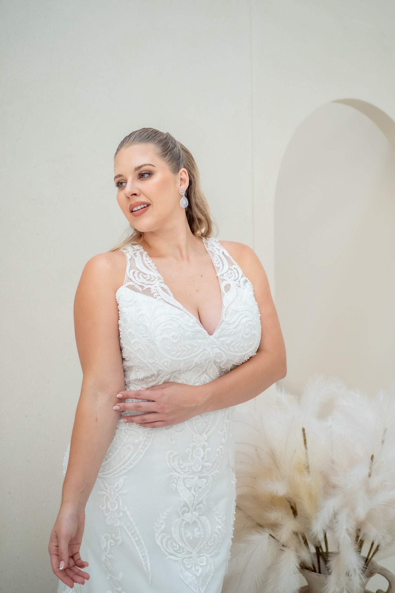 Woman wearing a white lace wedding dress with a neutral background