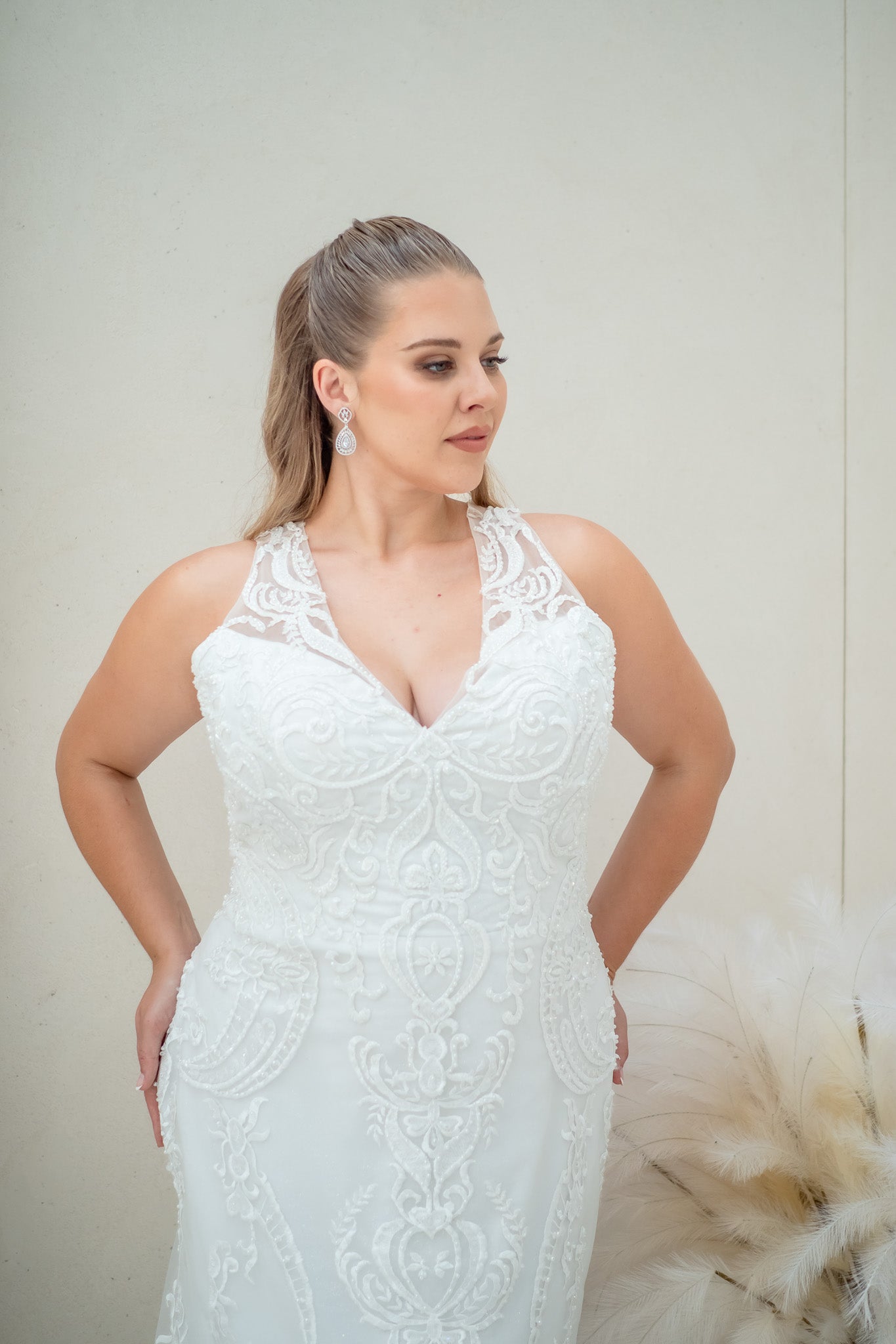 Woman wearing a white lace wedding dress against a neutral background