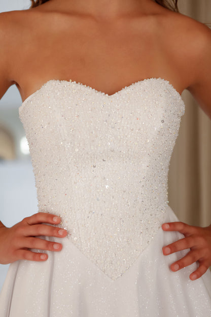White strapless wedding dress with bead detailing on a blurred background
