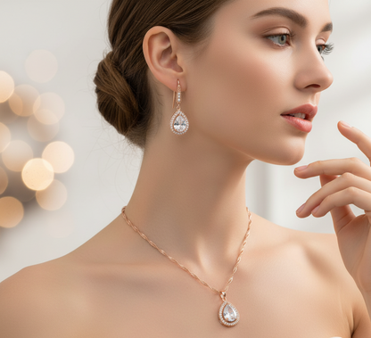 Woman wearing a rose gold necklace and teardrop earrings with a blurred bokeh background
