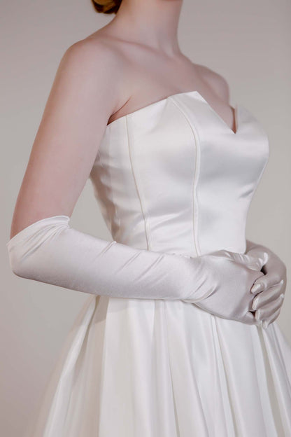 White strapless gown with long gloves on a plain background