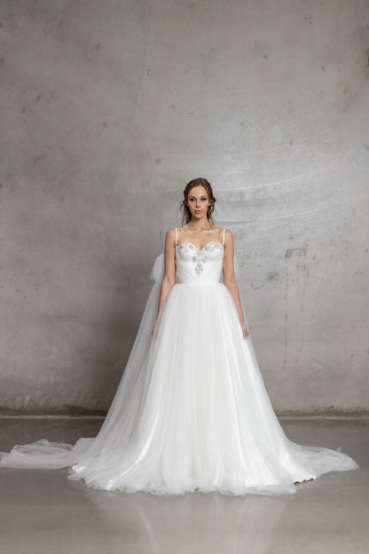 White wedding dress with intricate detailing on a plain background