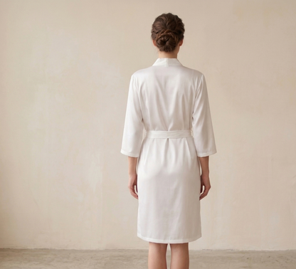 Person wearing a white robe against a plain background