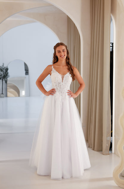 Woman in a white wedding dress standing in a bright, elegant room with arches.