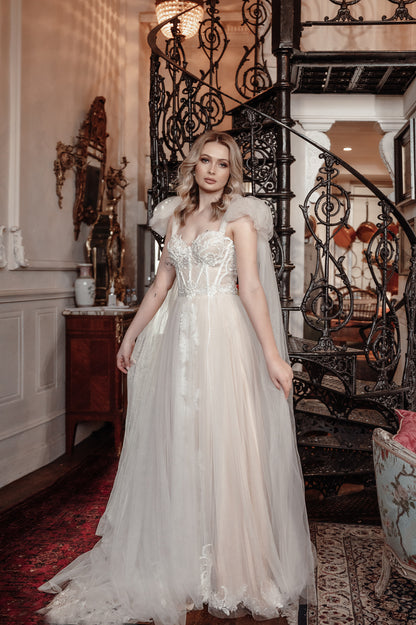 Woman in a white wedding dress standing in an elegant interior setting with a staircase