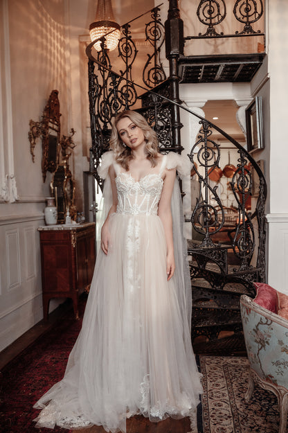 Woman in a white wedding dress standing in an elegant interior setting with a staircase